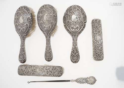 AN EDWARDIAN SILVER BRUSH SET, EMBOSSED WITH TRELLIS AND ROCAILLE, BY WILLIAM M HAYES, BIRMINGHAM