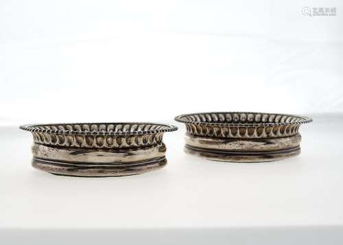 A PAIR OF GEORGE III GADROONED SILVER WINE COASTERS, INSET TURNED WOOD BASE WITH CRESTED SILVER
