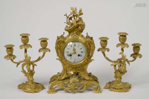 一套路易十五风格的三件式镀金青铜壁炉，包括：一对带三根灯臂的烛台和一个时钟。时期：约1900年。(刀片运动)。高度：从28到39厘米。