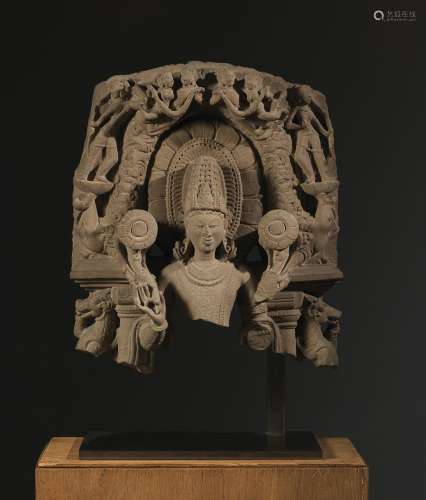 Surya印度 约10°-12°世纪砂岩。54 x 46 cm一块大型石碑的上半部分，描绘太阳神，可从其肩上的莲花辨认。在神灵的两边还可以看到靠在背板柱子上的vyalas和支撑在树干上支撑次要神灵的makaras。古代事故和可见的失误。来源：Compagnie de la Chine et des Indes (Paris) (Inv.23462 1990年收购)