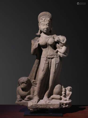 Ambika印度约10°世纪砂岩。高98厘米印度教徒和耆那教教徒都敬仰的女神的重要代表。在这里，她左手抱着一个孩子站着，她的第二个孩子可能是她脚下的小人，在狮子后面，那是她的车。出处：Compagnie de la Chine et des Indes (Paris) (Inv.21958 1974年12月从Spink & Son London购得)。