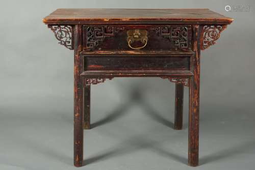 中国，20世纪。小工作桌正面由一个雕花抽屉打开。四角有雕刻和镂空装饰。漆木。磨损。漆面褪色。(尺寸待定)