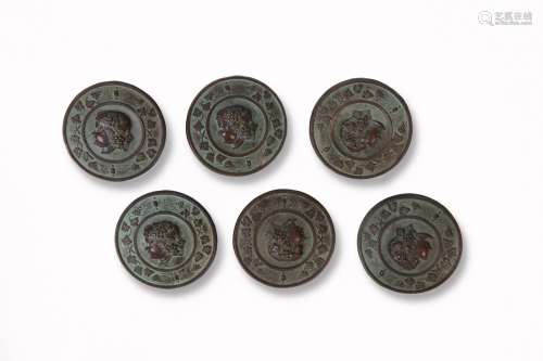 一套六枚圆形金属纽扣，带有棕色/绿色的铜锈，纽扣上的巴克斯头像轮廓被藤蔓包围。直径：4厘米。罕见的模型。19世纪初。