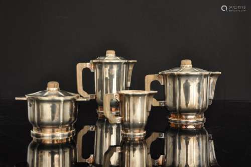 ERCUIS茶具和咖啡具由镀银金属制成，包括一个茶壶、一个咖啡壶、一个牛奶壶和一个糖碗。黑檀木把手和手柄（磨损）。底部有厄尔库斯的标记。装饰艺术风格。茶壶的高度：15厘米 - 咖啡壶的高度：18厘米 - 糖碗的高度：10厘米。