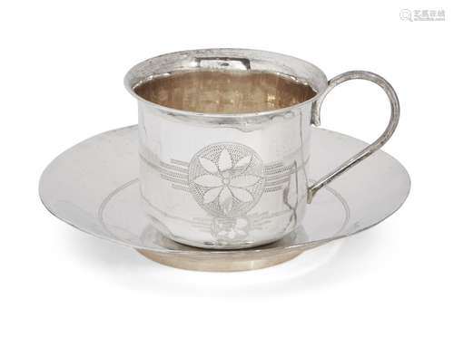 A bright-cut engraved cup and saucer, unmarked white metal, both decorated with flower motif and