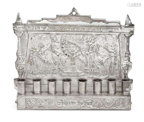 An eight branch silver plated menorah, mounted with eight candle holders to a repousse plaque with