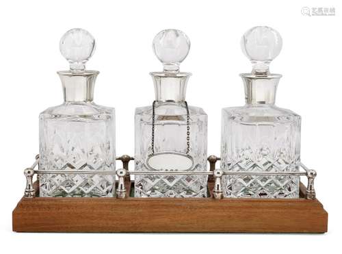 A pair of silver mounted glass decanters on wooden base, Birmingham, c.1985 and 1988, Charles S