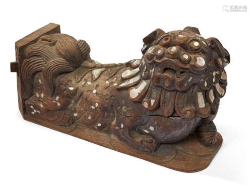 A Chinese hardwood and mother of pearl inlaid Buddhist lion, 19th century, carved in recumbent pose,