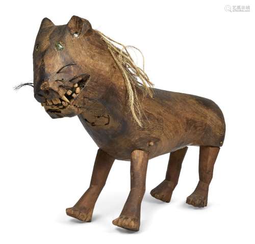 A folk art carved hardwood model of a lion, 19th century, with inset glass eyes, coarse hair