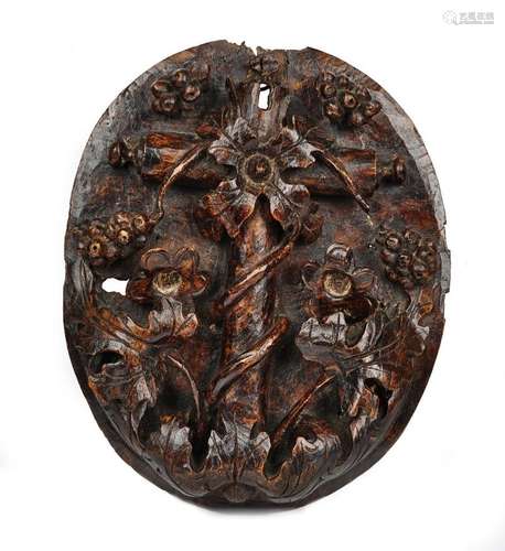 A 17th century Italian walnut oval panel relief carved with a fruiting vine,