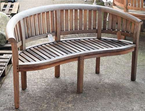 A teak framed semi-elliptic garden bench with slatted back and seat on block supports,