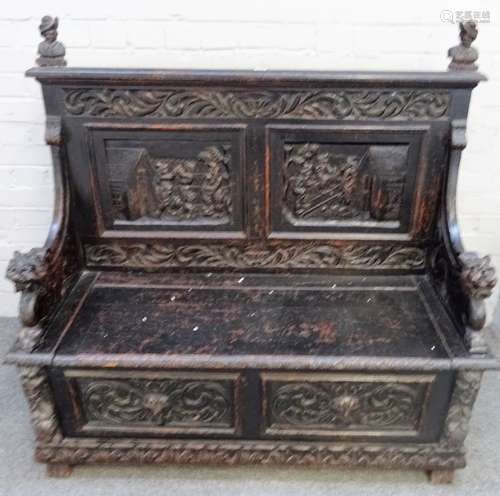 A late 19th century carved oak box seat settle, with recumbent beast arm supports,