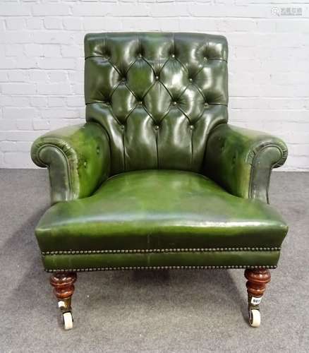 A Victorian green leather upholstered easy armchair, on turned mahogany supports,