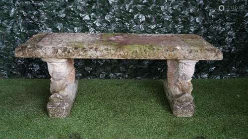 A reconstituted stone garden bench on serpent trestle supports, 130cm wide,