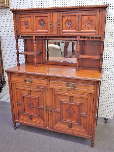 An Aesthetic Movement walnut side cabinet, with four flower carved doors over bevelled mirror,