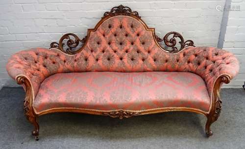 A Victorian carved and pierced walnut framed tub back sofa, with serpentine seat on scroll supports,