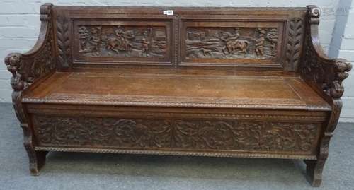 Edwards and Roberts; a carved oak box seat settle, with beast arm finials, 142cm wide x 78cm high.