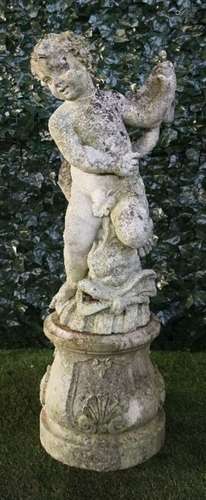 A reconstituted stone figure group of a cherub riding a serpent, on a circular baluster base,