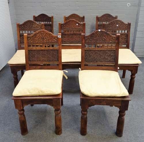 A set of eight Indian hardwood dining chairs with floral trellis carved back on turned supports,