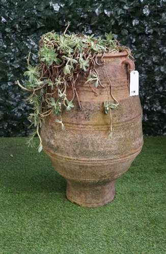 A large terracotta oil jar with ribbed body and three lug handles, 50cm wide x 85cm high.