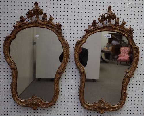 A pair of Victorian gilt framed shaped wall mirrors with scrolling crests and leaf chased frames,