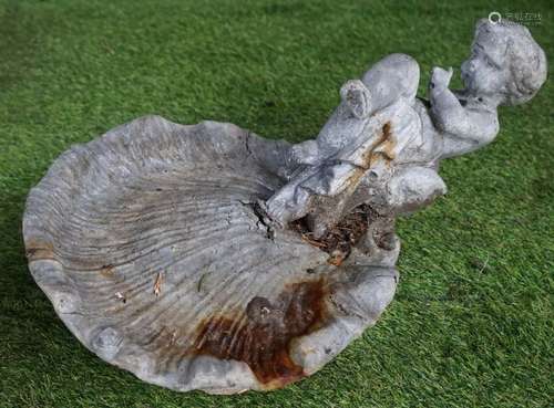 A lead bird bath modelled as a cherub sitting on a shell, 50cm wide x 30cm high.