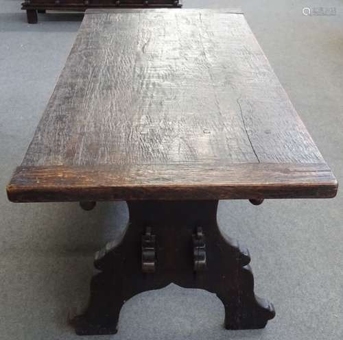 A 19th century Italian oak plank top kitchen table on trestle end standards united by double