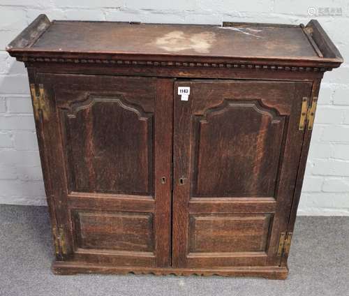 An 18th century oak hanging cupboard with pair of arched panel doors enclosing a fitted interior,