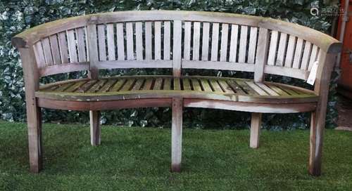 A teak framed semi-elliptic garden bench with slatted back and seat, on block supports,