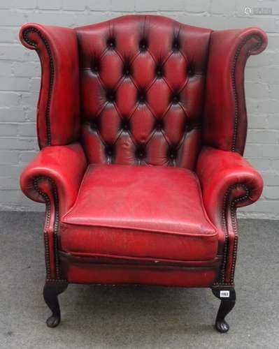 A red leather upholstered George I style wingback armchair on cabriole supports,