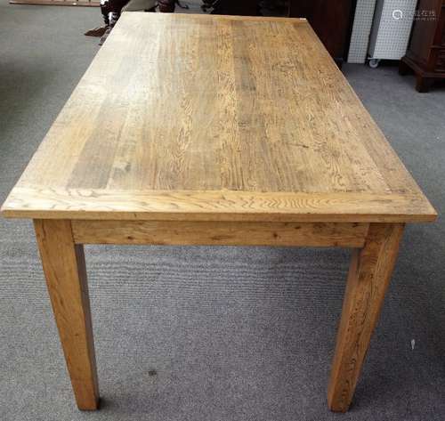 A modern distressed oak kitchen table, the cleated plank top on tapering square supports,