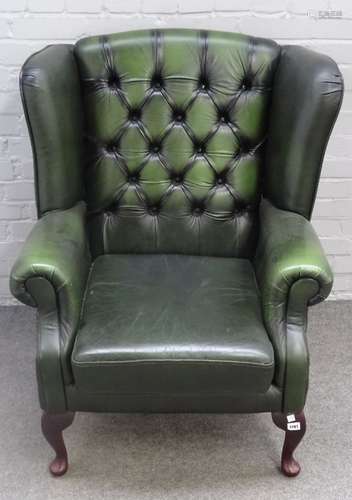 A green leather upholstered George I style wingback armchair on cabriole supports,