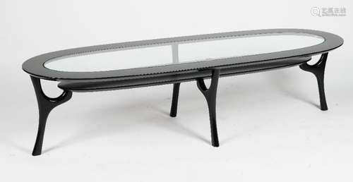 A black lacquered oval 'racetrack' coffee table, with glass inset top and undertier,