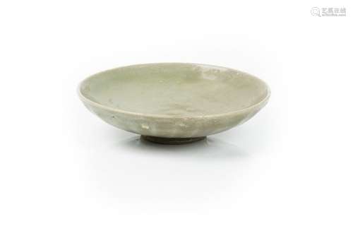 A Chinese celadon dish, Ming dynasty, the underside moulded with lappets beneath a dark green glaze,