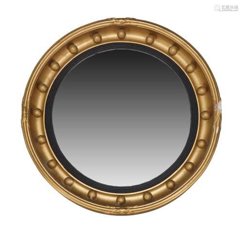 A Regency-style gilt framed circular wall mirror, 19th Century, the convex plate set within ebonised