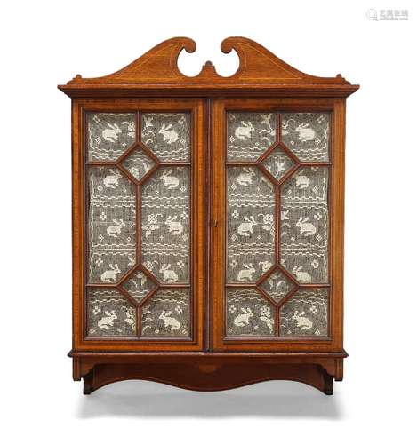 An Edwardian mahogany and satinwood banded wall cabinet, with swan neck pediment above two