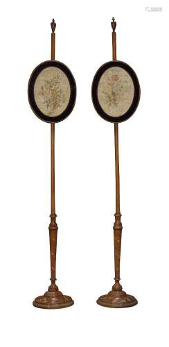 A pair of painted satinwood oval pole screens, each with urn finial, the adjustable screens
