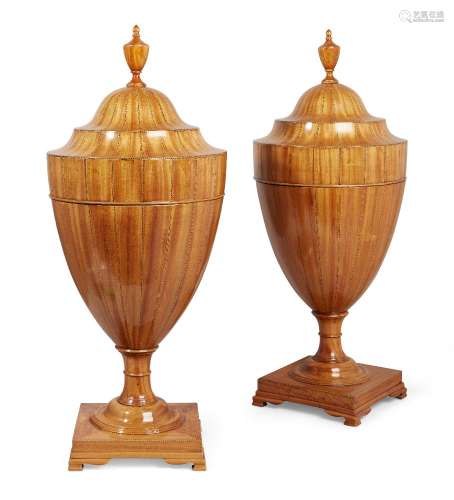 A pair of George III Sheraton satinwood cutlery urns, the urn finials above boxwood and ebony