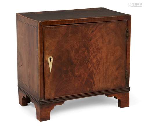 A George III satinwood miniature spice cupboard, the single door enclosing nine drawers, on