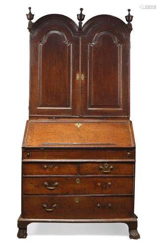 A Queen Anne oak bureau bookcase, the top surmount with three urn shaped finials above twin arched