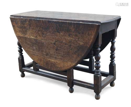 An oak gate leg table, 18th century, the oval top with two drop leaves, on turned baluster form