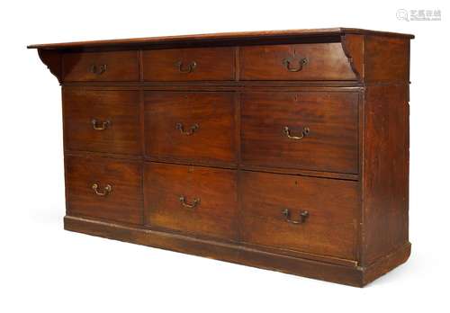 A Georgian mahogany store cabinet, the rectangular top with hinged flap, over nine drawers, raised