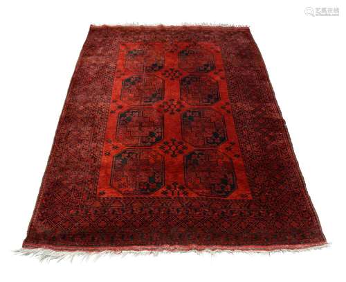 An Afghan rug, mid to late 20th century, with two rows of octagons in a deep red field, 270cm x