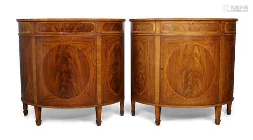 A pair of Edwardian flame mahogany demi lune cabinets, with single drawer over cupboard door with