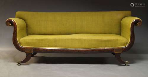 A Regency rosewood and brass inlaid sofa, with scrolling armrests and green fabric upholstery, on