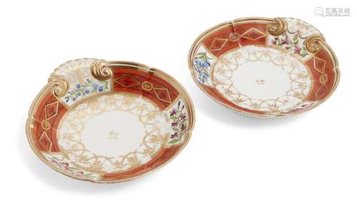 A pair of Sevres style orange and white ground dishes, with gilt scalloped rims and a trio of floral