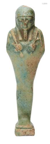 An Egyptian green glazed composition shabti, the uninscribed body depicted holding a pick and hoe