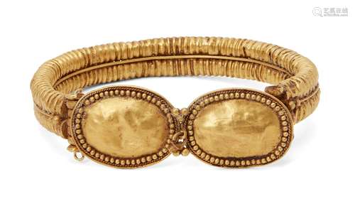 A reproduction Greek-style hollow gold bracelet with ribbed band and hinged terminals with a