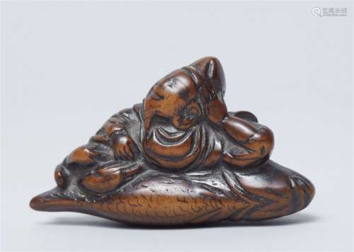 A boxwood netsuke of Ebisu lying on a sea bream. 18th centur...