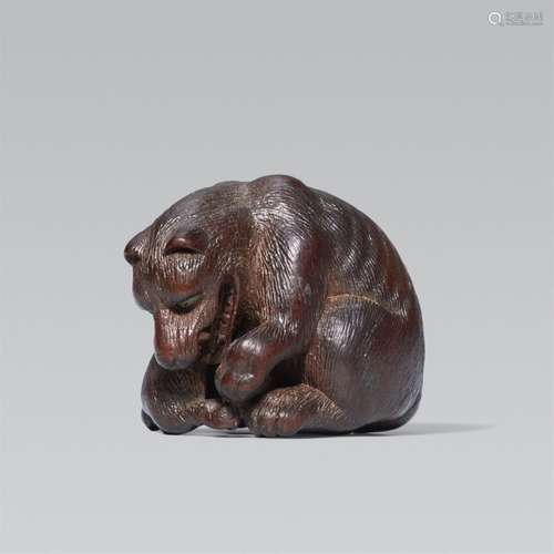 A wood netsuke of a wolf with a stag leg. Second half 19th c...